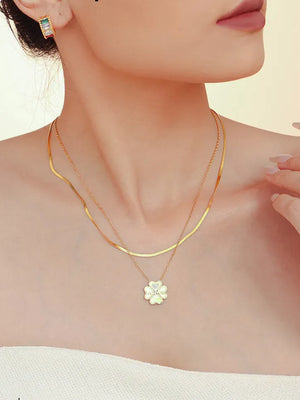 Gold layered necklace with a white clover charm and diamond detail