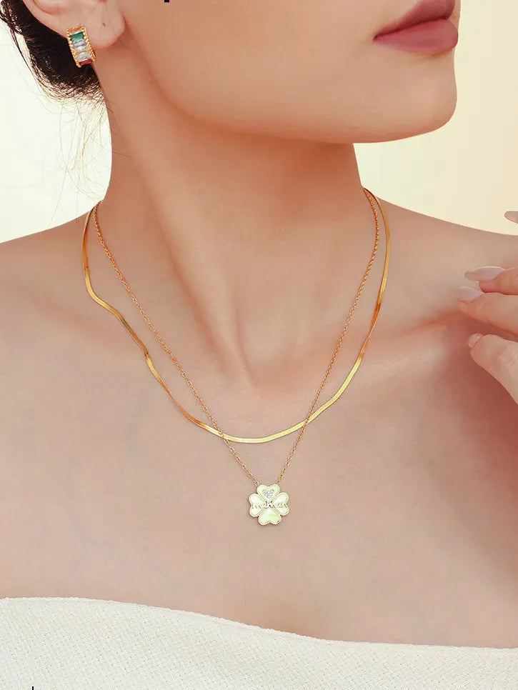 Gold layered necklace with a white clover charm and diamond detail