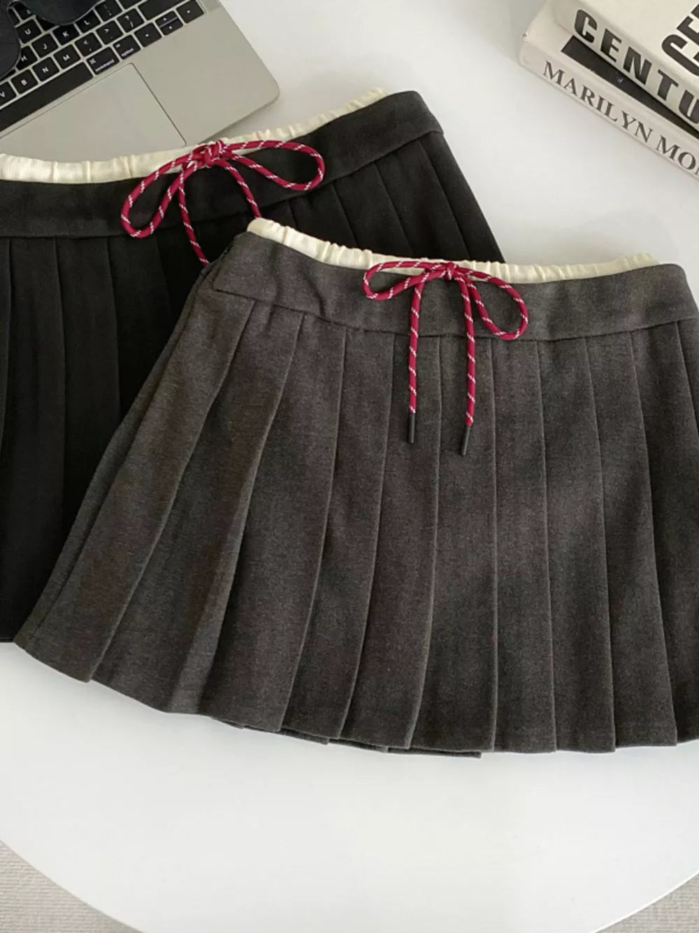 Chic drawstring pleated skirt in dark gray and black with white trim and red-striped ties.