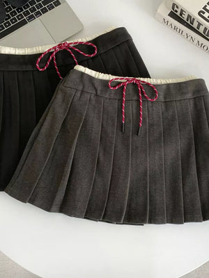 Chic drawstring pleated skirt in dark gray and black with white trim and red-striped ties.