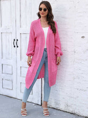 Pink ribbed knit maxi cardigan with pockets and balloon sleeves, styled with jeans.