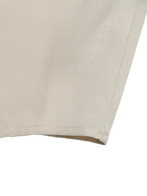Beige maternity overshirt with ruffle sleeves and tie-neck detail, showing fabric texture.