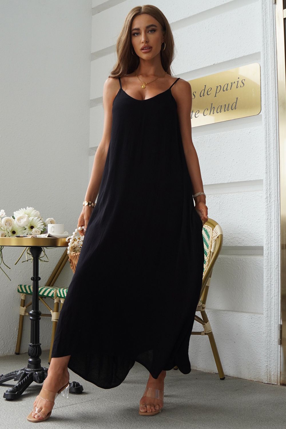 Black linen maxi dress with spaghetti straps and pockets, styled casually.