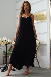 Black linen maxi dress with spaghetti straps and pockets, styled casually.
