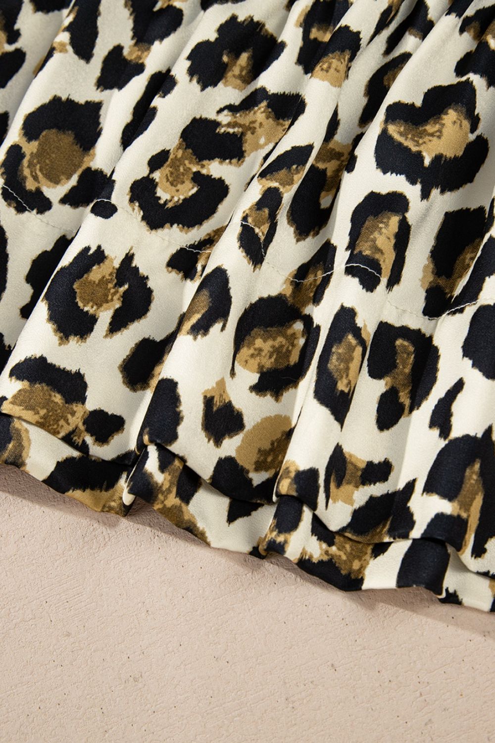Leopard print tie-neck peplum blouse with ruffled hem detail.