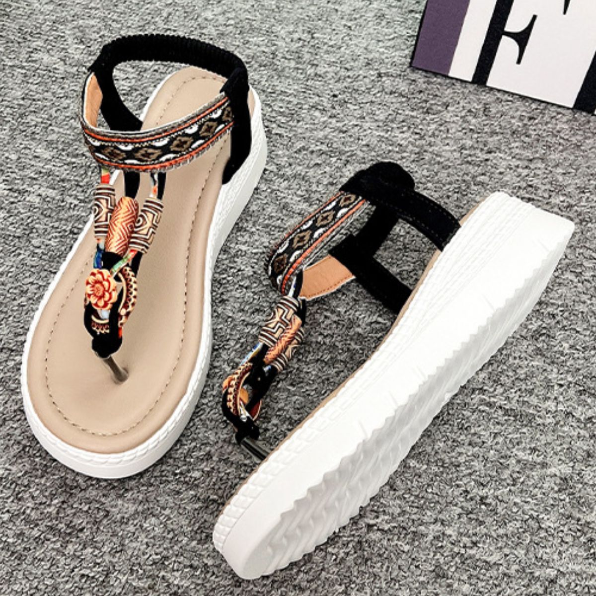 Ethnic patterned wedge sandals with floral accents and ankle straps in black and beige.