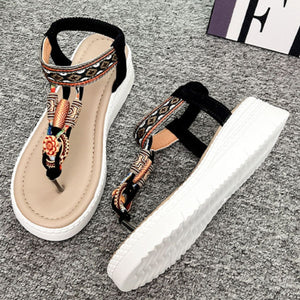 Ethnic patterned wedge sandals with floral accents and ankle straps in black and beige.