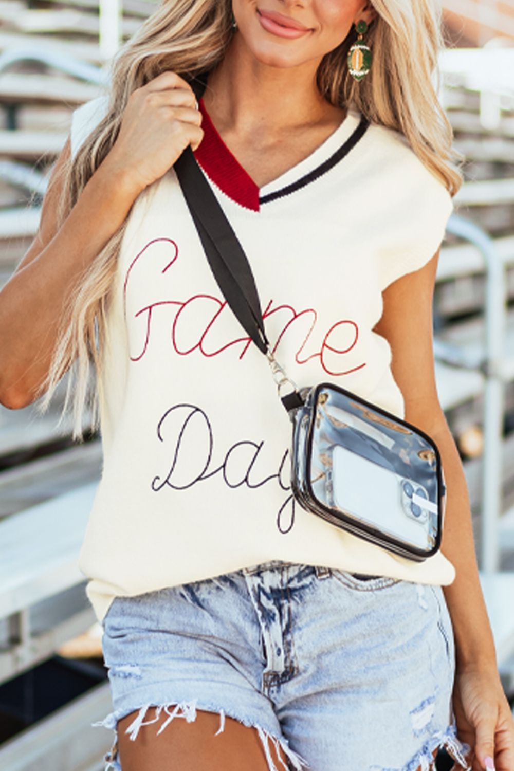 White knit vest with embroidered Game Day text, burgundy and black trim, V-neck, and clear crossbody bag.