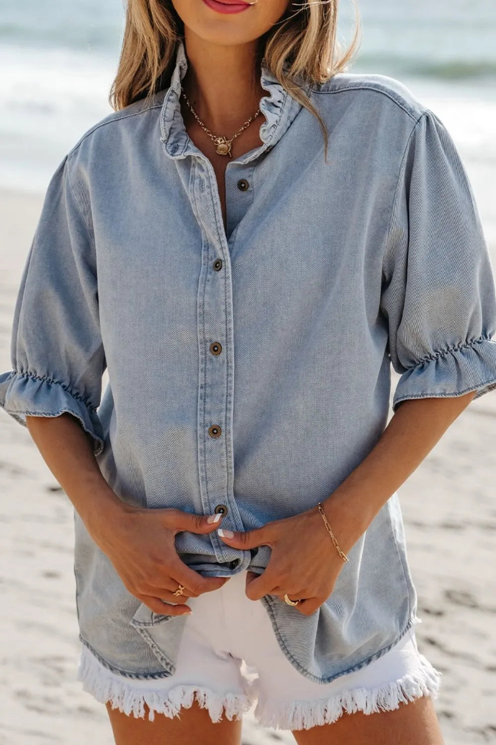 Light blue denim blouse with ruffled collar and puff sleeves, button front.