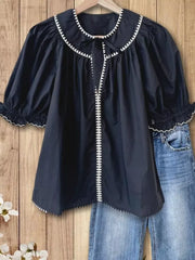 Navy polyester blouse with scalloped collar, tie-neck, puff sleeves, and white trim.