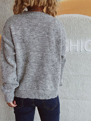 Gray knit crewneck sweater with ribbed cuffs and hem, featuring an embellished bow detail on the front.