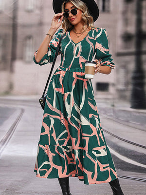 Midi dress in mid green with abstract print, smocked waist, V-neck, and tiered hem.