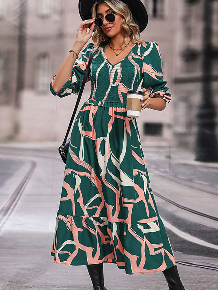 Midi dress in mid green with abstract print, smocked waist, V-neck, and tiered hem.