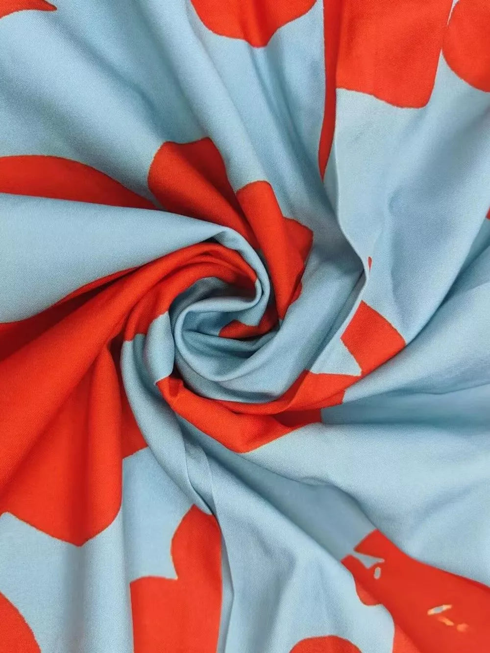 Maxi dress fabric with vibrant red floral print on light blue.