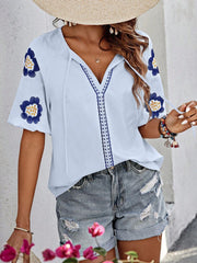 Light blue embroidered yoke sleeve blouse with floral details and tie neckline.