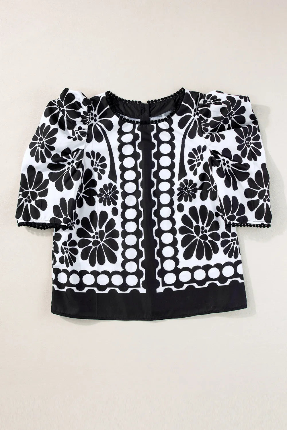 Black floral puff sleeve blouse with button back and pom-pom trim.