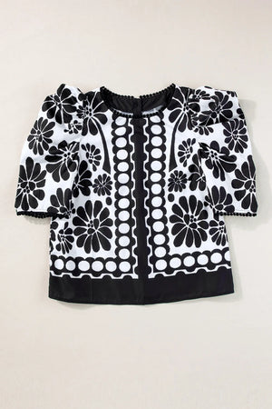 Black floral puff sleeve blouse with button back and pom-pom trim.