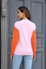 Colorblock crewneck knit sweater with pink body and orange sleeves.