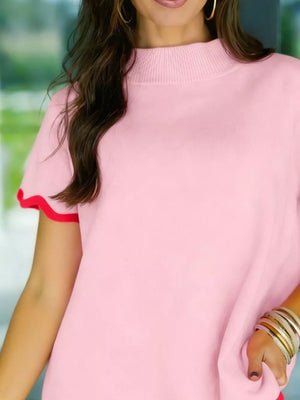 Chic pink ribbed knit sweater with wavy red trim on sleeves and mock neck.