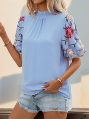 Light blue blouse with smocked mock neck and sheer organza sleeves with floral embroidery.