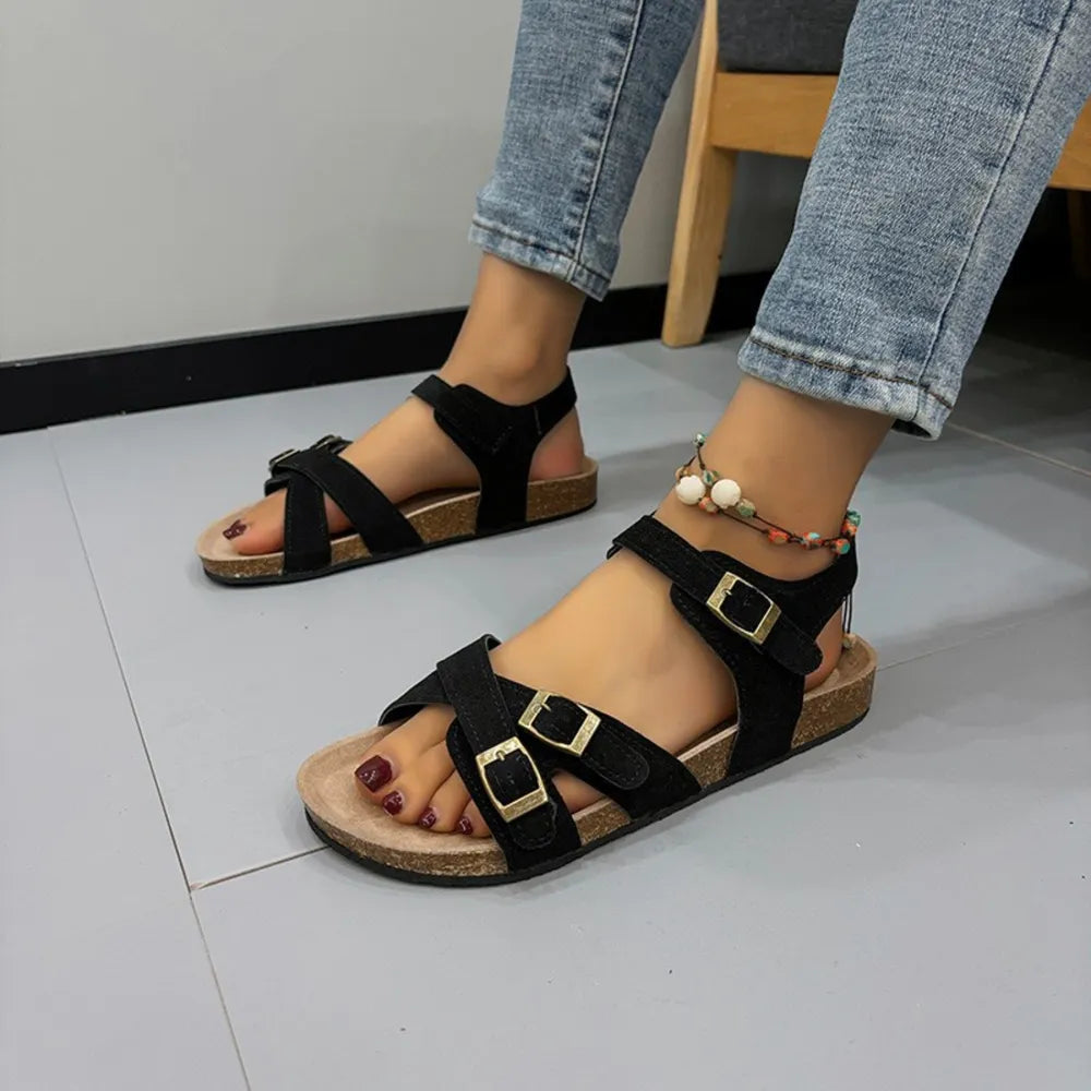 Black suede crossover buckle cork sandals with adjustable straps.
