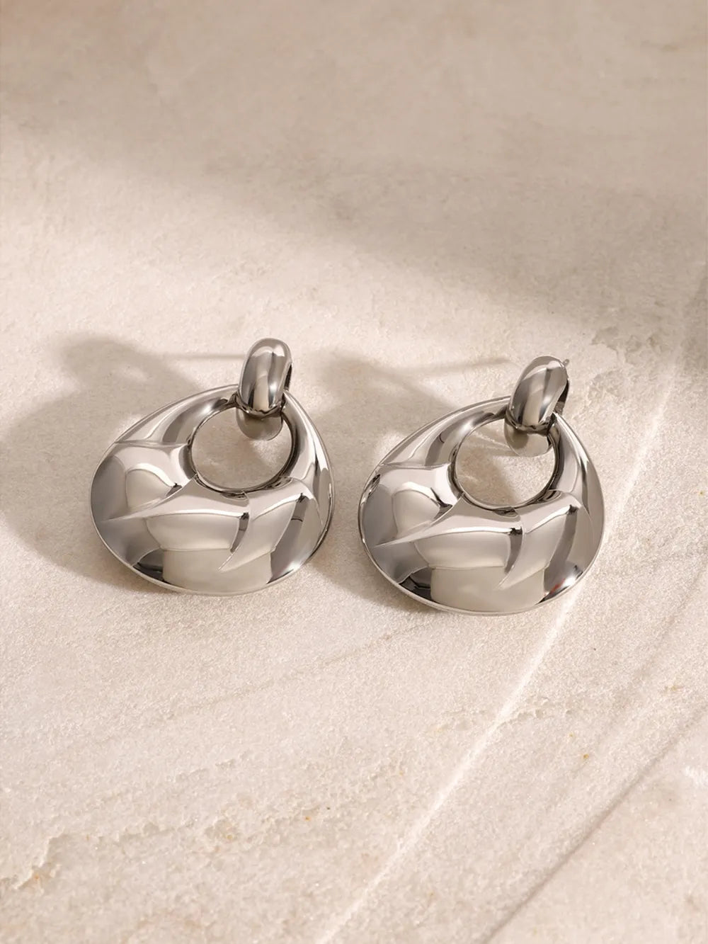 Sculpted silver statement earrings with textured detail and a chic, modern design.