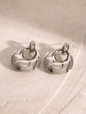 Sculpted silver statement earrings with textured detail and a chic, modern design.