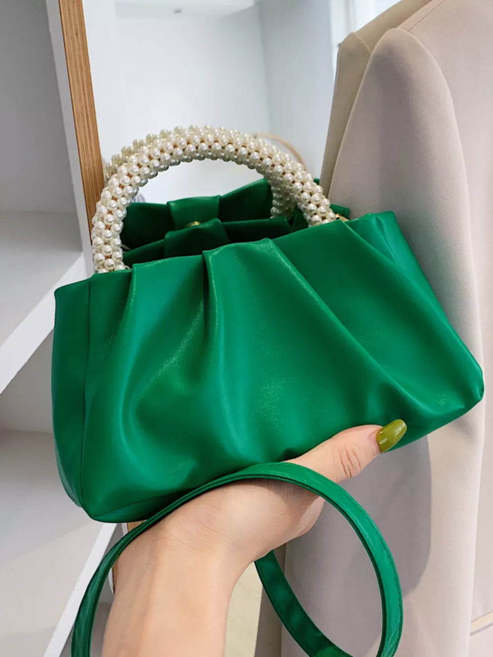 Green ruched crossbody bag with pearl handle and a removable strap.