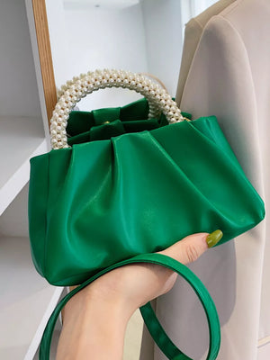 Green ruched crossbody bag with pearl handle and a removable strap.