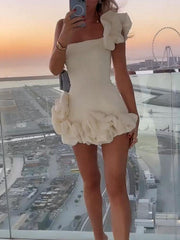 White ruffled one-shoulder mini dress with a fitted bodice and voluminous skirt detail.