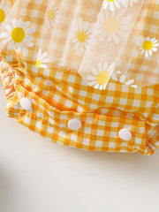 Yellow gingham baby one-piece with daisy print tulle overlay and snap closure.