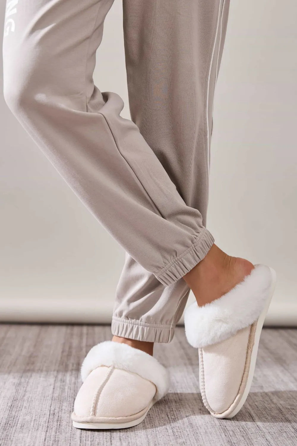 Beige suede house slides with plush white shearling trim.
