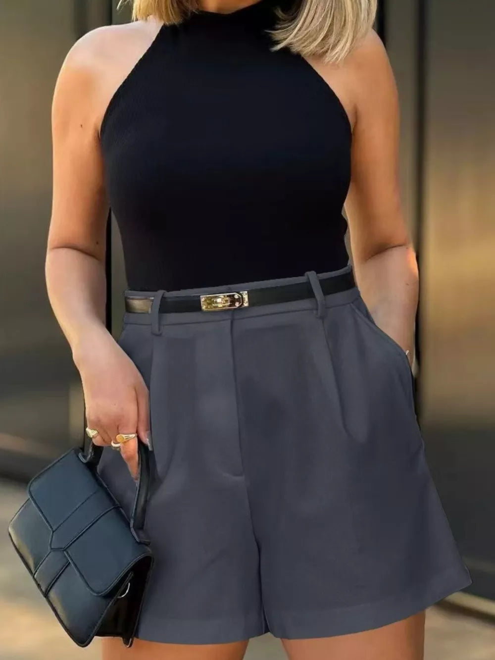 Dark gray high-waisted shorts with pleats and pockets, styled with a black top and belt.