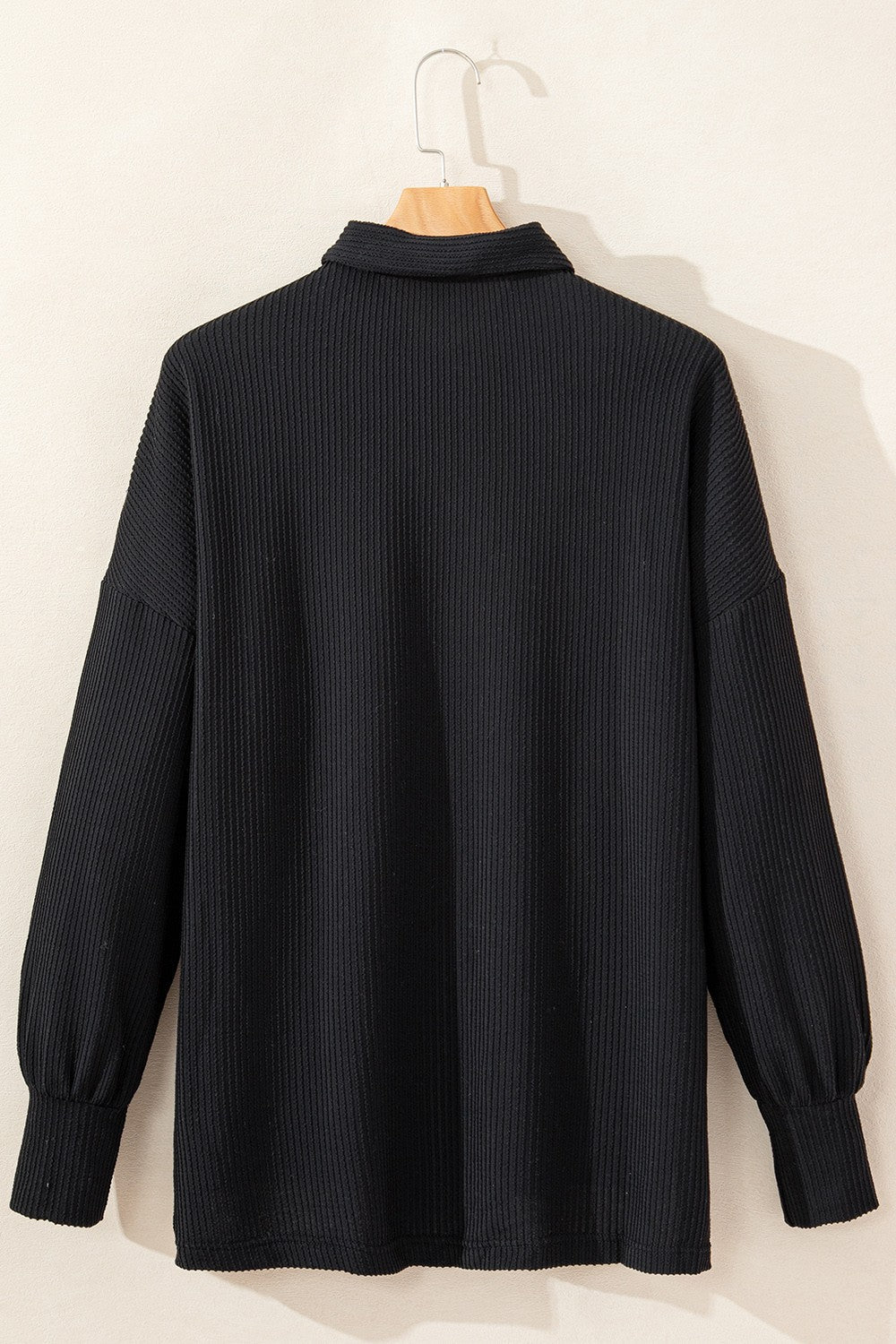 Black textured knit shirt jacket with collar and buttoned front, balloon sleeves.
