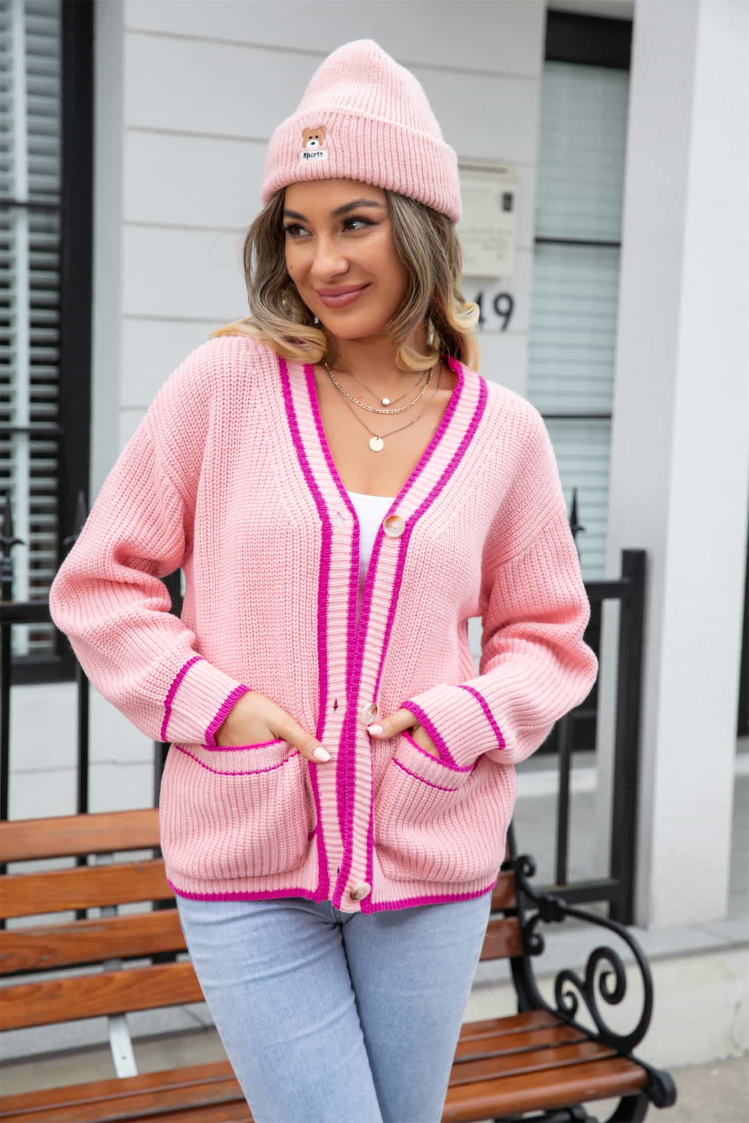 Pink acrylic cardigan with contrast trim and pockets, V-neck, button front, long sleeves.