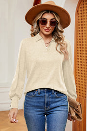 Cream buttoned blouse with V-neck and balloon sleeves, detailed with cuff buttons.