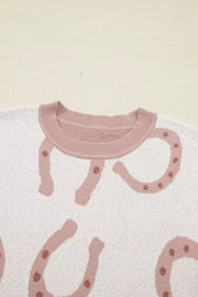 White knit top with pink horseshoe pattern and crew neck.