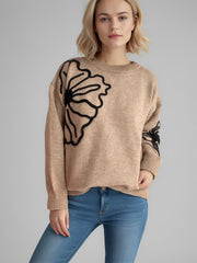 Tan knit sweater with black floral embroidery on chest and sleeve.