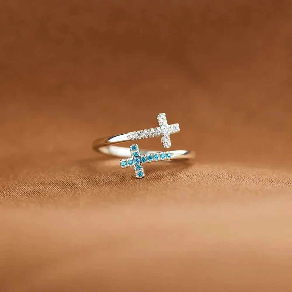 Sterling silver ring with two intertwined crosses, one with clear stones, one with blue stones.
