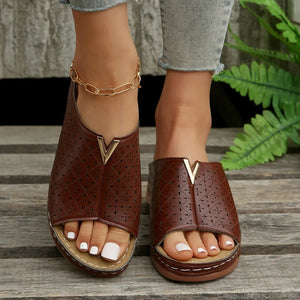 Brown laser-cut leather platform slides with V-shaped gold accent and open toe.