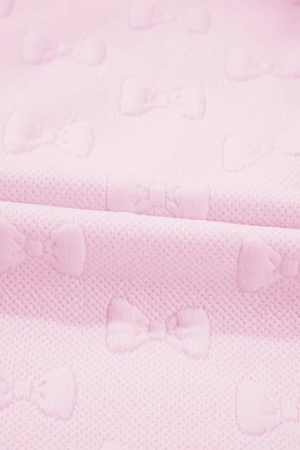 Blush pink loungewear set with embossed bow pattern and ruffle sleeves.