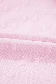 Blush pink loungewear set with embossed bow pattern and ruffle sleeves.