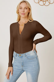 Brown ribbed bodysuit with plunge neckline and zipper detail, styled with light wash jeans.