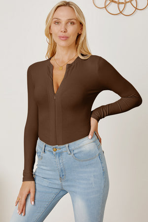 Brown ribbed bodysuit with plunge neckline and zipper detail, styled with light wash jeans.