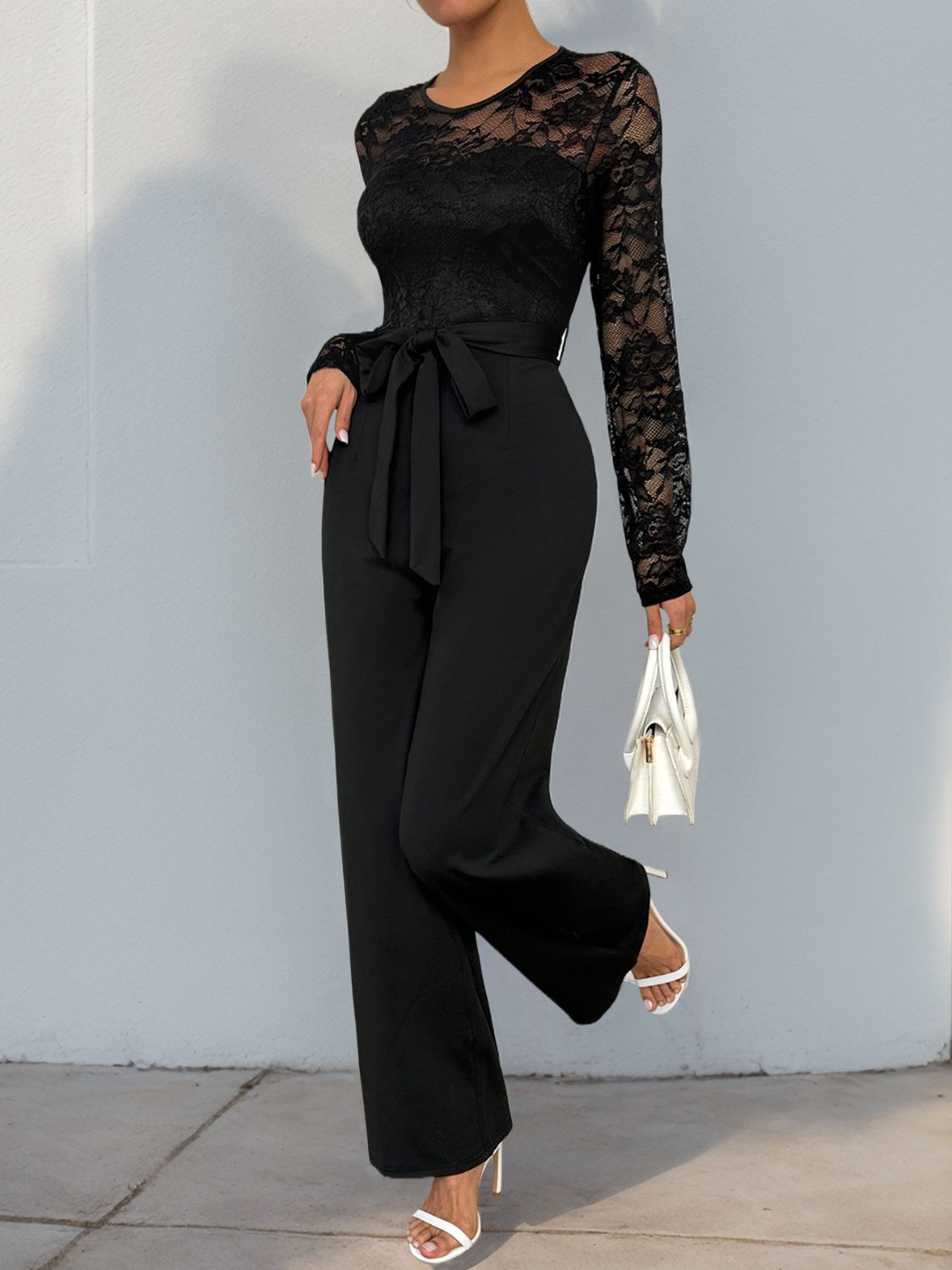 Black lace bodice wide-leg jumpsuit with tie waist and long sleeves.