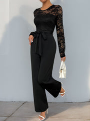 Black lace bodice wide-leg jumpsuit with tie waist and long sleeves.