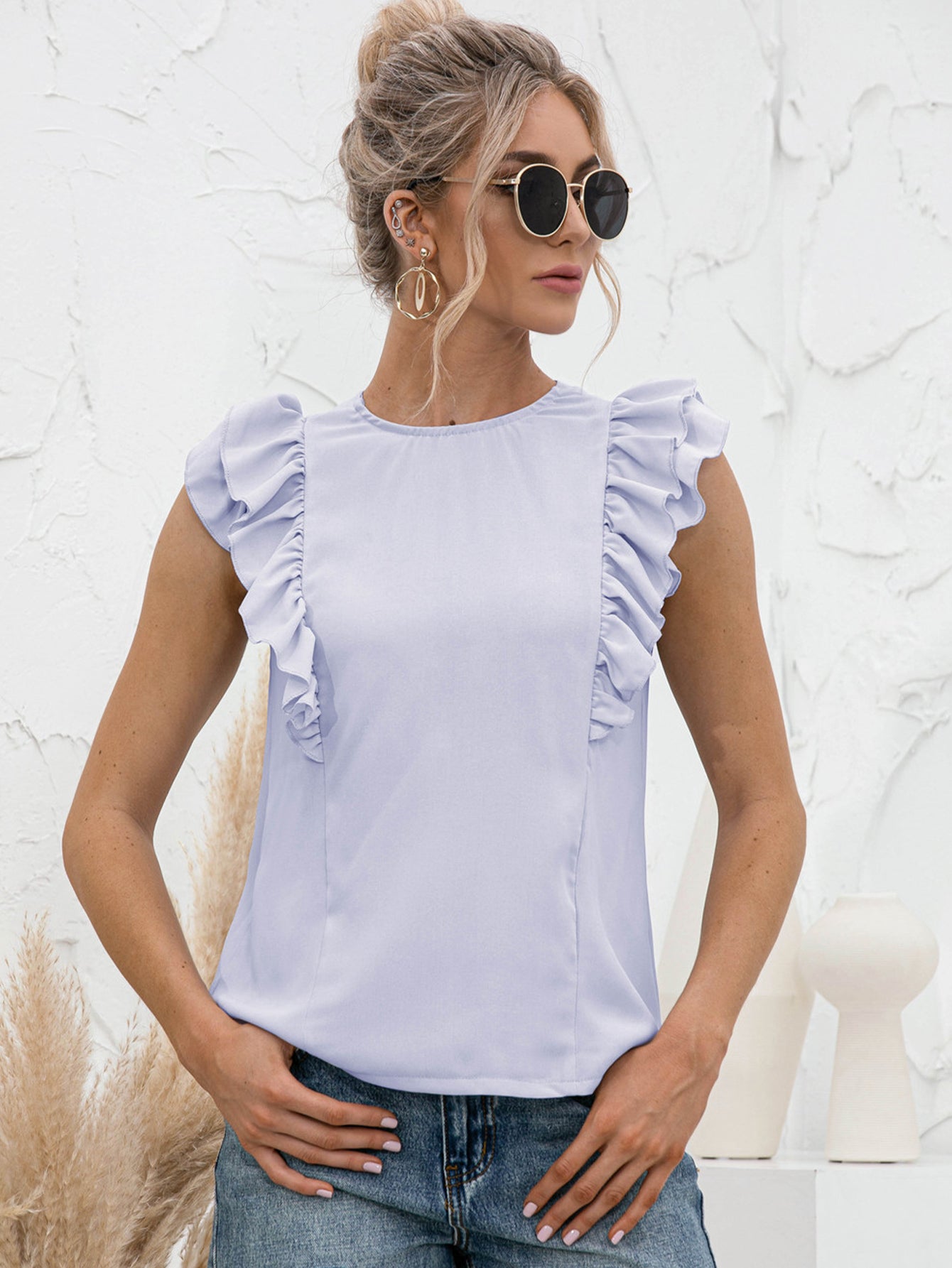 Light blue ruffled yoke sleeveless blouse with a round neckline.