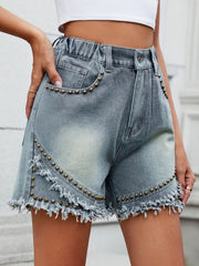 Medium wash denim shorts with studded trim and frayed fringe hem.