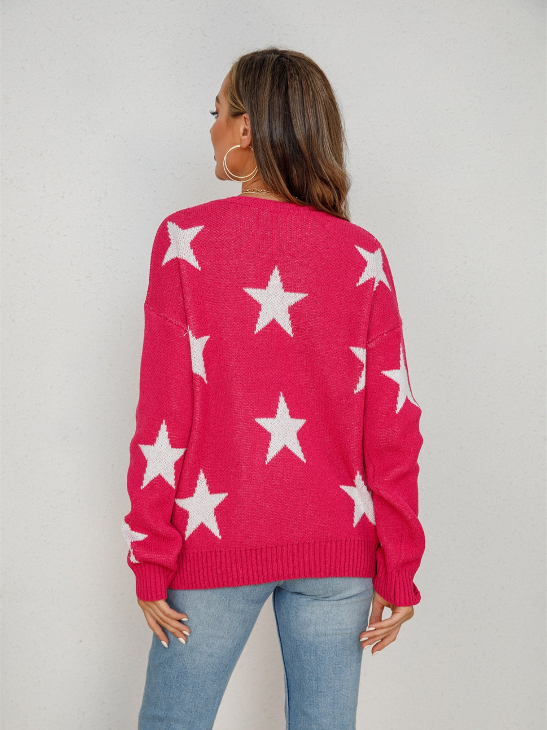 Pink knit crewneck sweater with white stars, long sleeves, ribbed cuffs and hem.