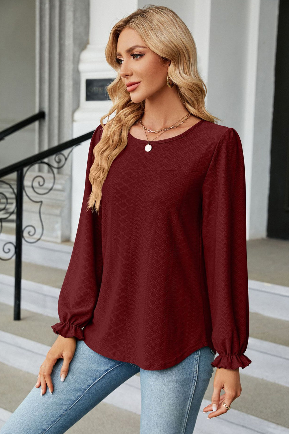 Burgundy textured puff sleeve blouse with ruffle cuffs and round neckline.